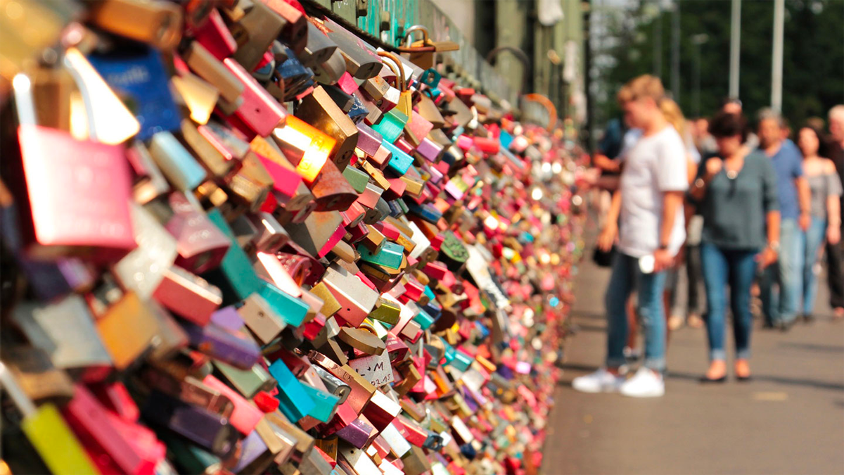 Close-up of many locks in the Love Lock Bridge in Paris with tourists blurred in the background 